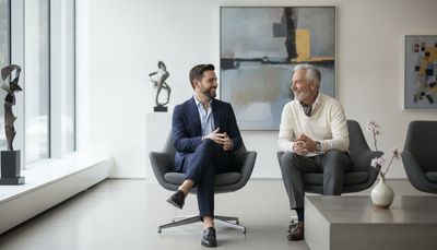 Zwei Männer unterhalten sich entspannt vor Kunstwerken in einer modernen Galerie